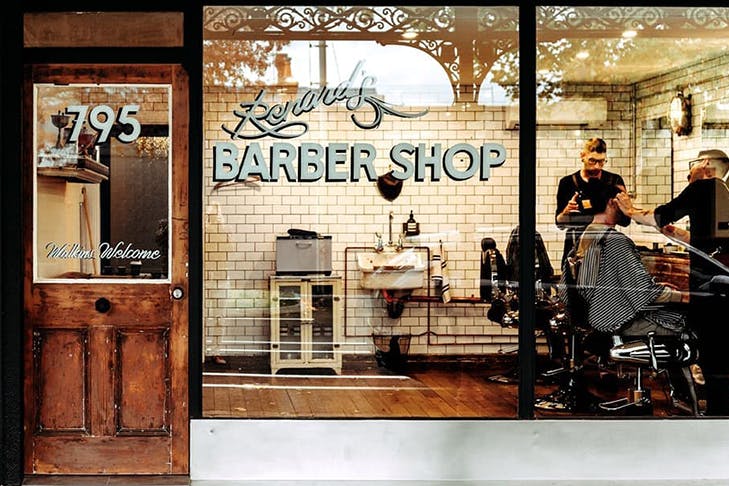 An old school barbershop with a sign on the window that reads